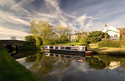 Boat moored by cottage in evening sunshine on the Cheshire Canal